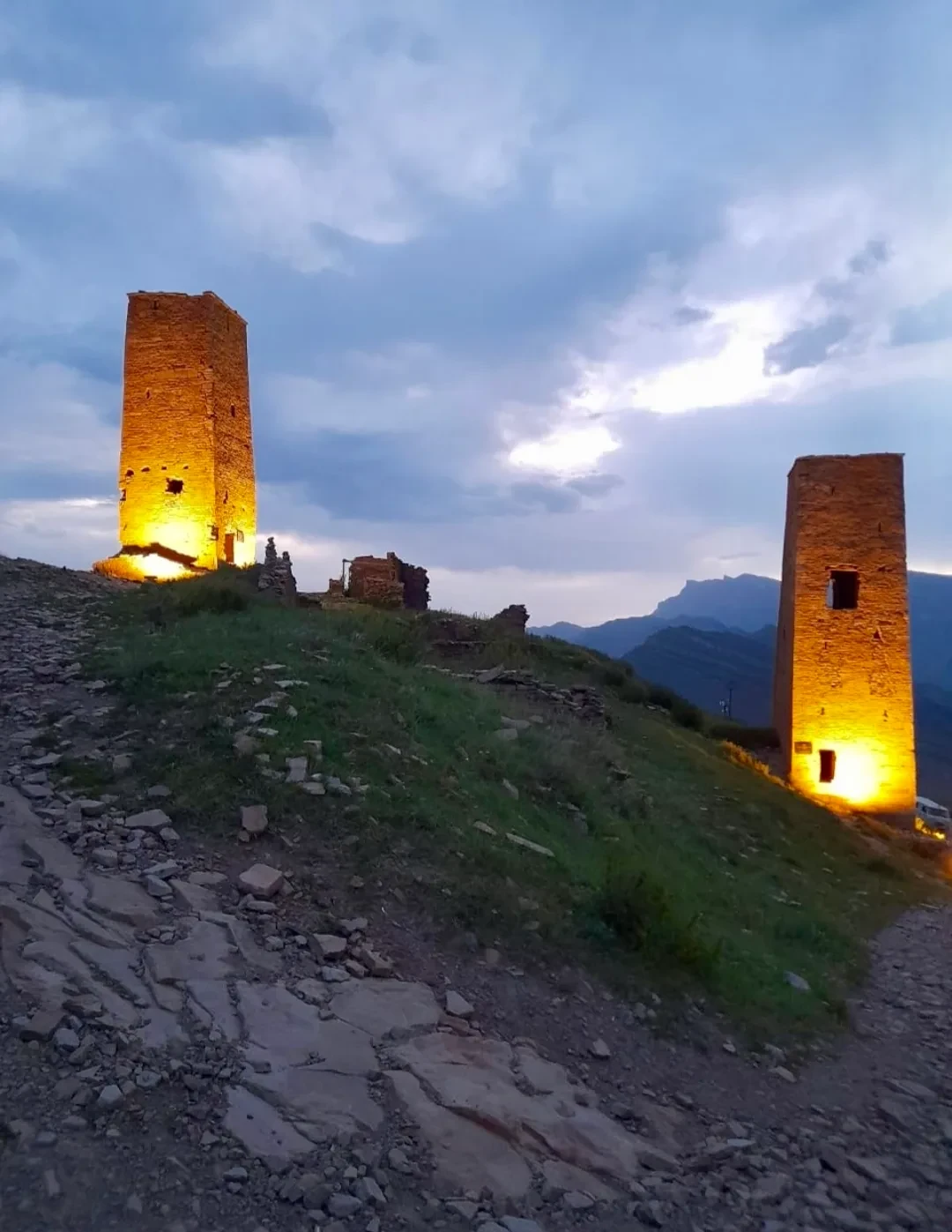 Две каменные башни с вечерней подсветкой на фоне сумеречного неба