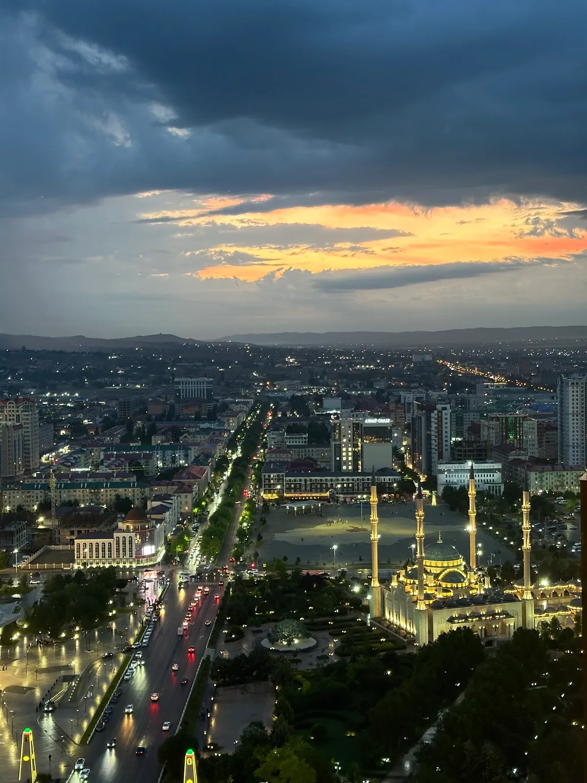 Ночная панорама города с освещённой мечетью и прямой улицей